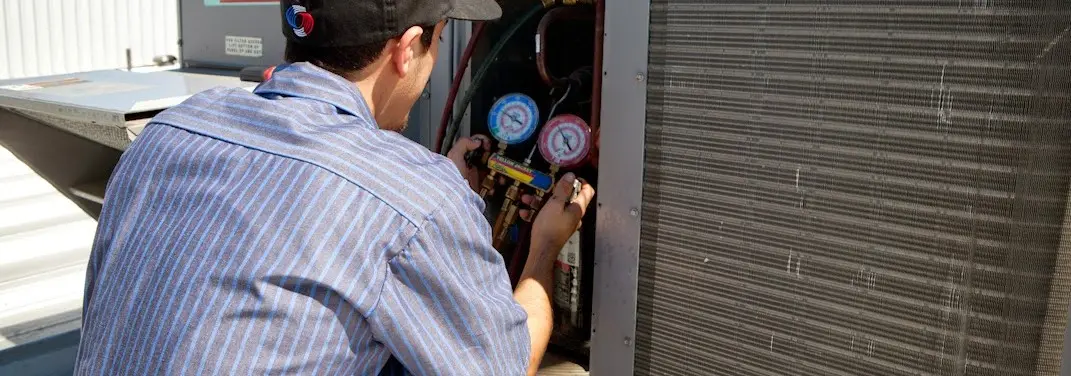 HVAC technician servicing a condenser unit in Rockdale