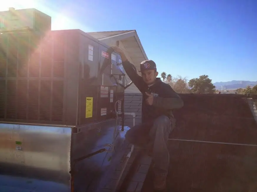 HVAC technician performing AC Tune-Up on a rooftop unit in Rockdale